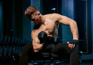 muscular sportsman building biceps with dumbbell